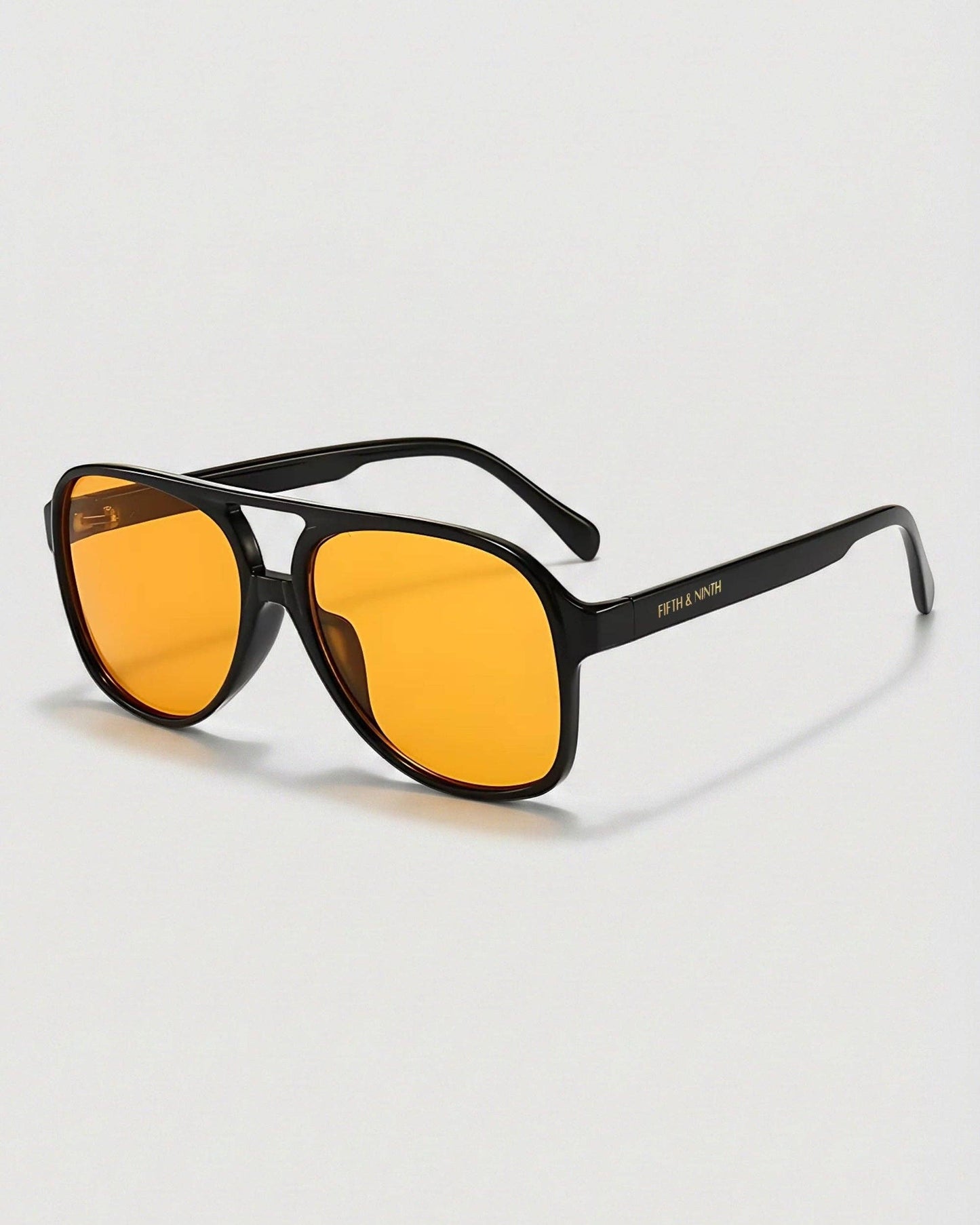 Sunglasses with yellow lenses and black frames on a light gray background