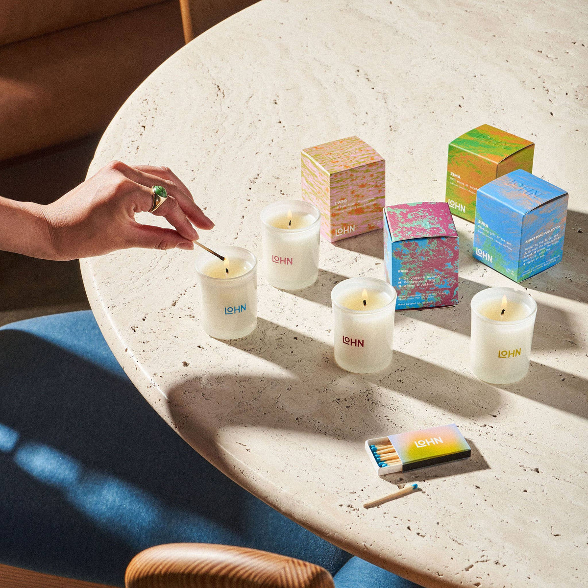 Person lighting candles on a table with colorful boxes in the background