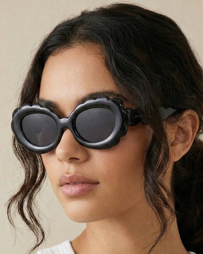 Person wearing heart-shaped sunglasses with a neutral background