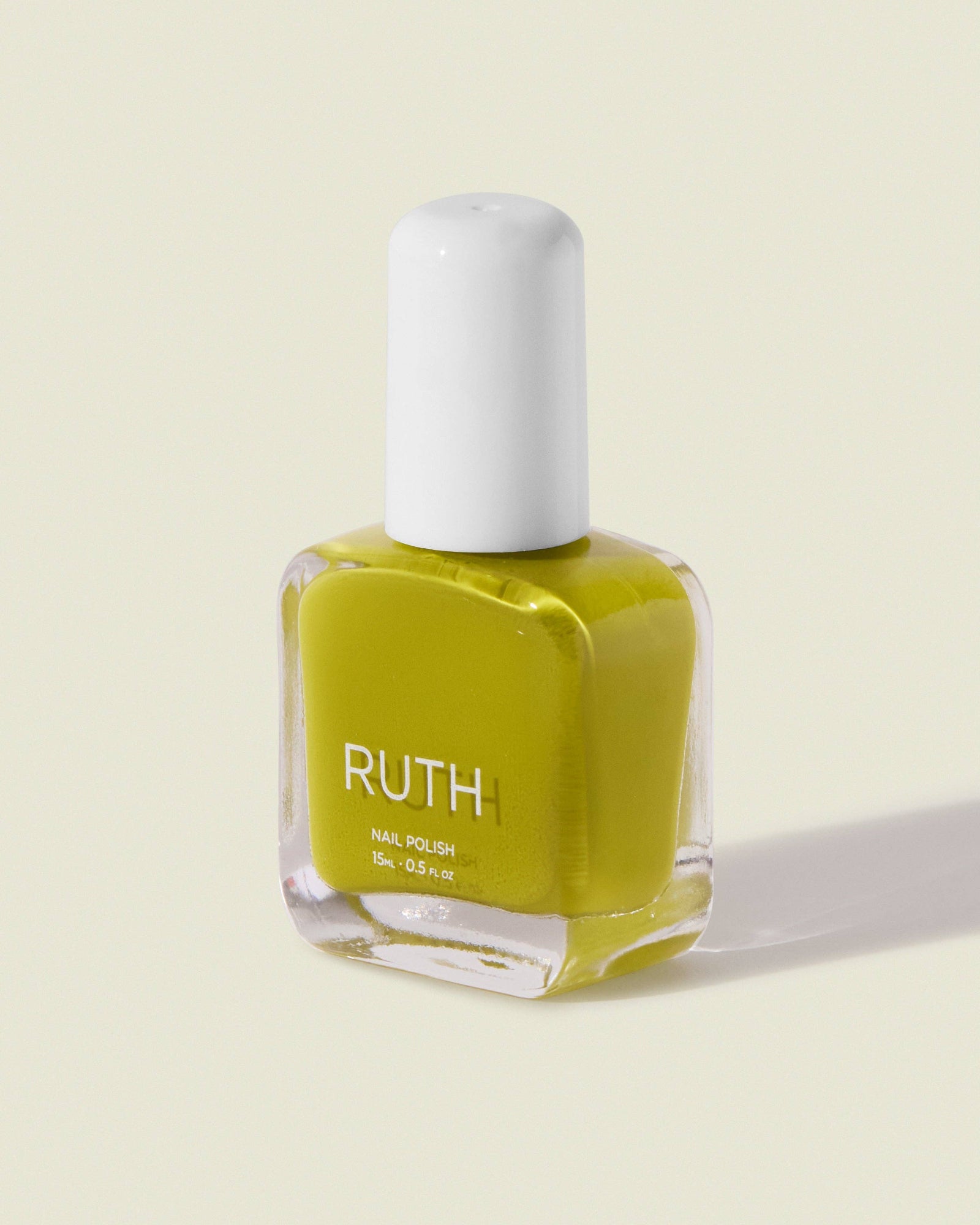 Yellow nail polish bottle with white cap on a light beige background, Lily Chartreuse Nail Polish