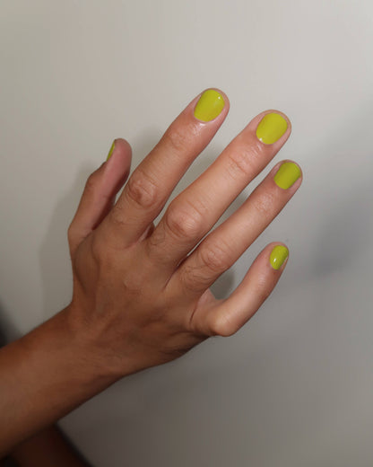 Hand with neon green nail polish on a plain background, Lily Chartreuse Nail Polish Ruth Polish