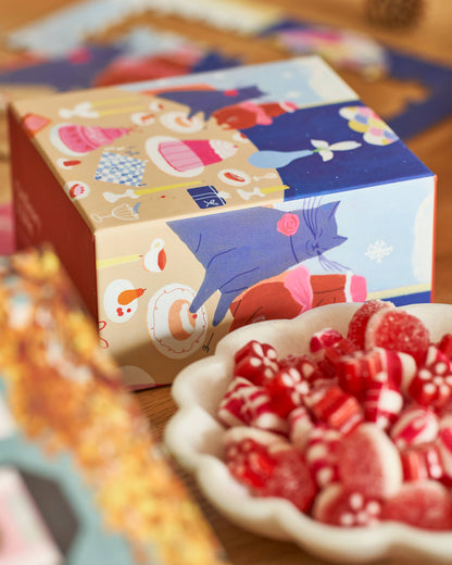 Colorful box with cartoon characters next to a bowl of red candies on a wooden surface