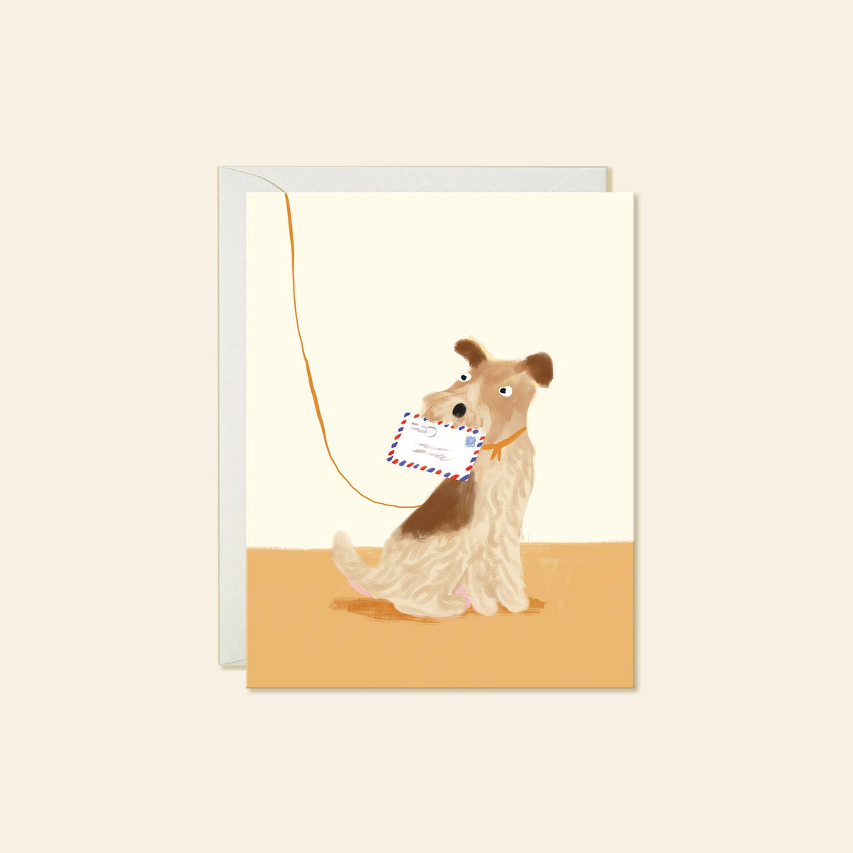 A greeting card with a white envelope behind it, featuring an illustration of a wirehaired dog holding a postcard on a leash, set against a warm cream and tan background.