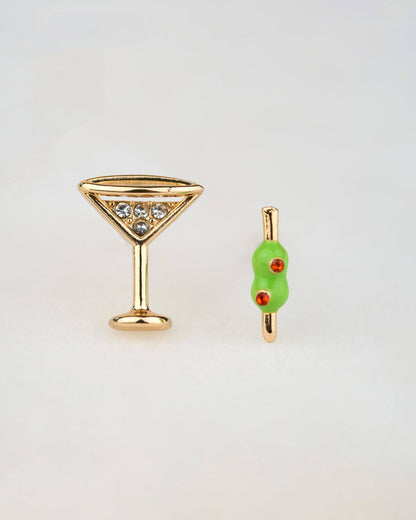 Gold martini glass and olive-shaped earring on a light gray background