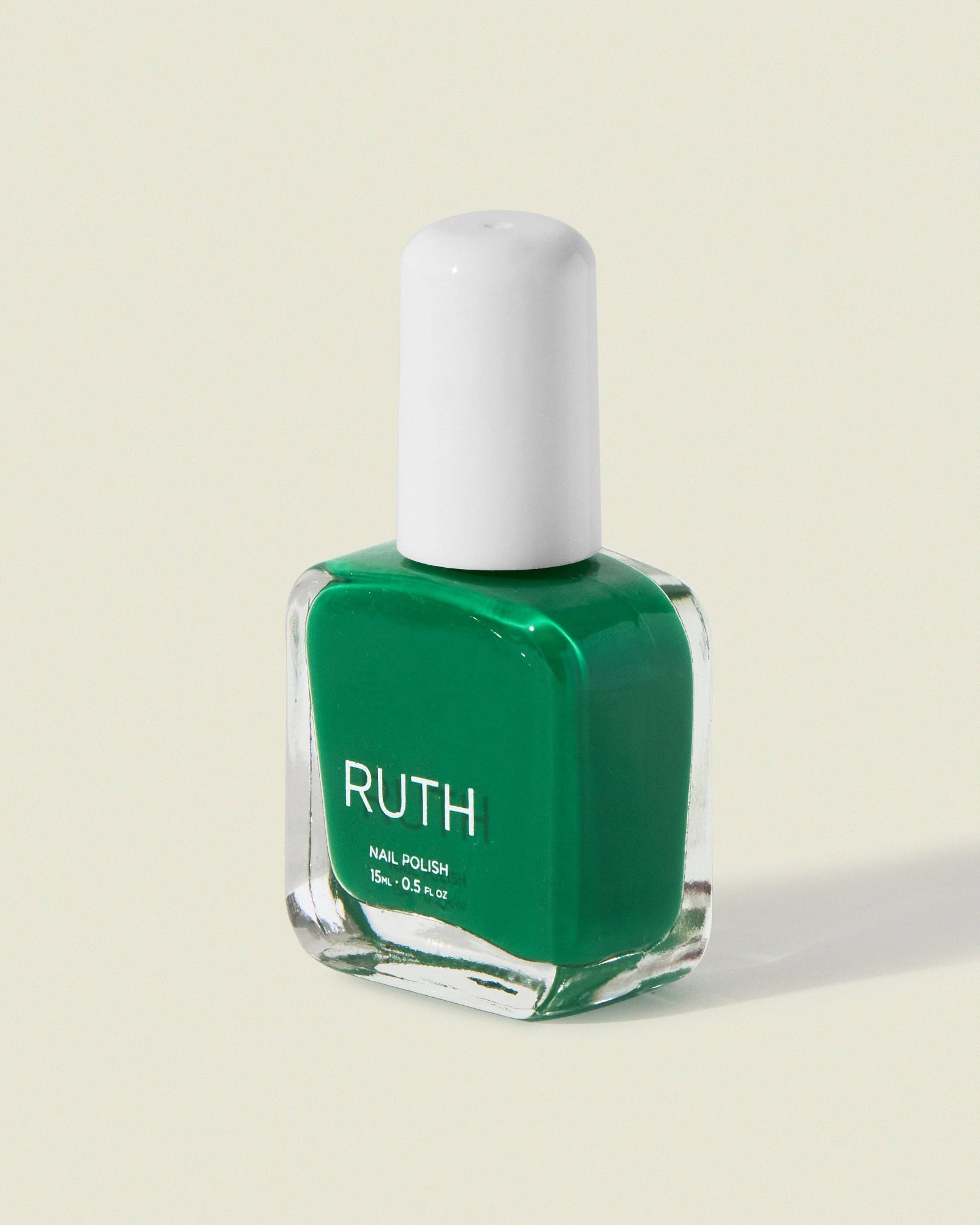Green nail polish bottle with white cap on a light beige background, Maryjane Medium Green Nail Polish