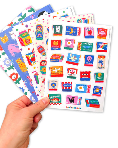 Colorful sticker sheets held by a hand on a white background