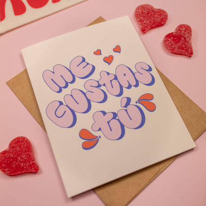 Card with 'Me Gustas Tó' text on a pink background with heart-shaped candies.