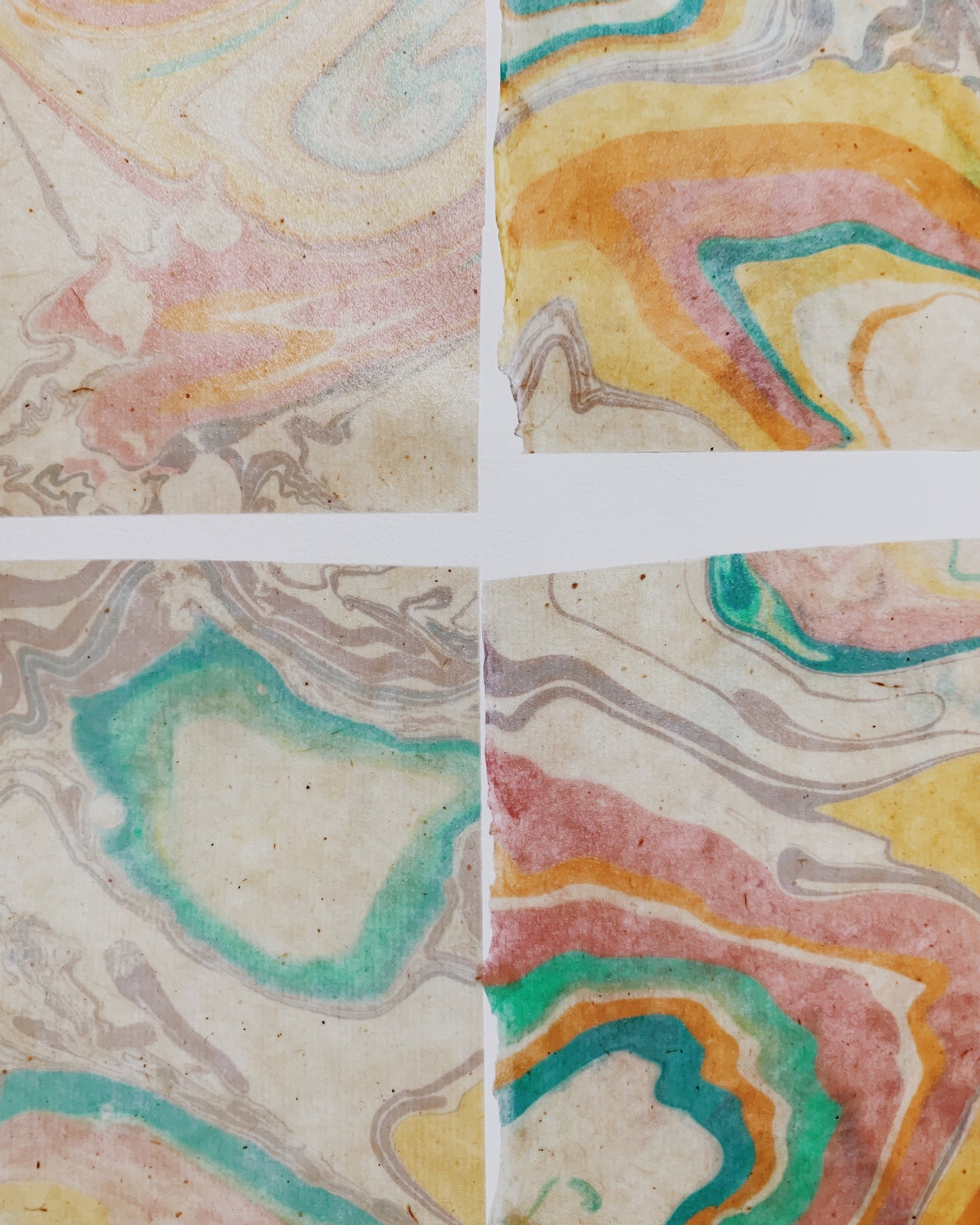 Four square tiles with marbled paper patterns in pastel colors.