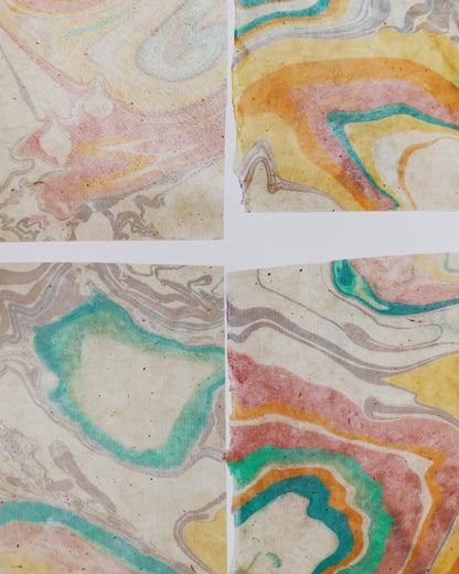 Four square tiles with marbled paper patterns in pastel colors.