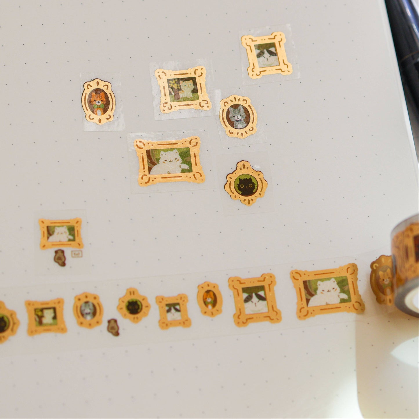 Decorative washi tape with gold frames and cat illustrations on a white surface.