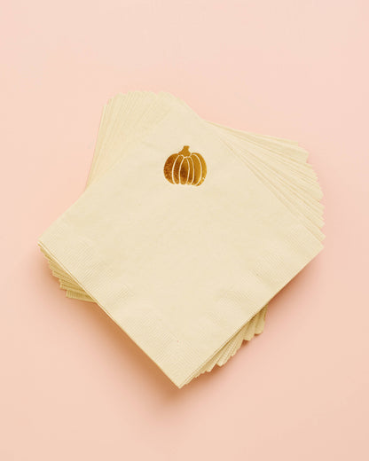 Stack of light green napkins with gold pumpkin design on a pink background