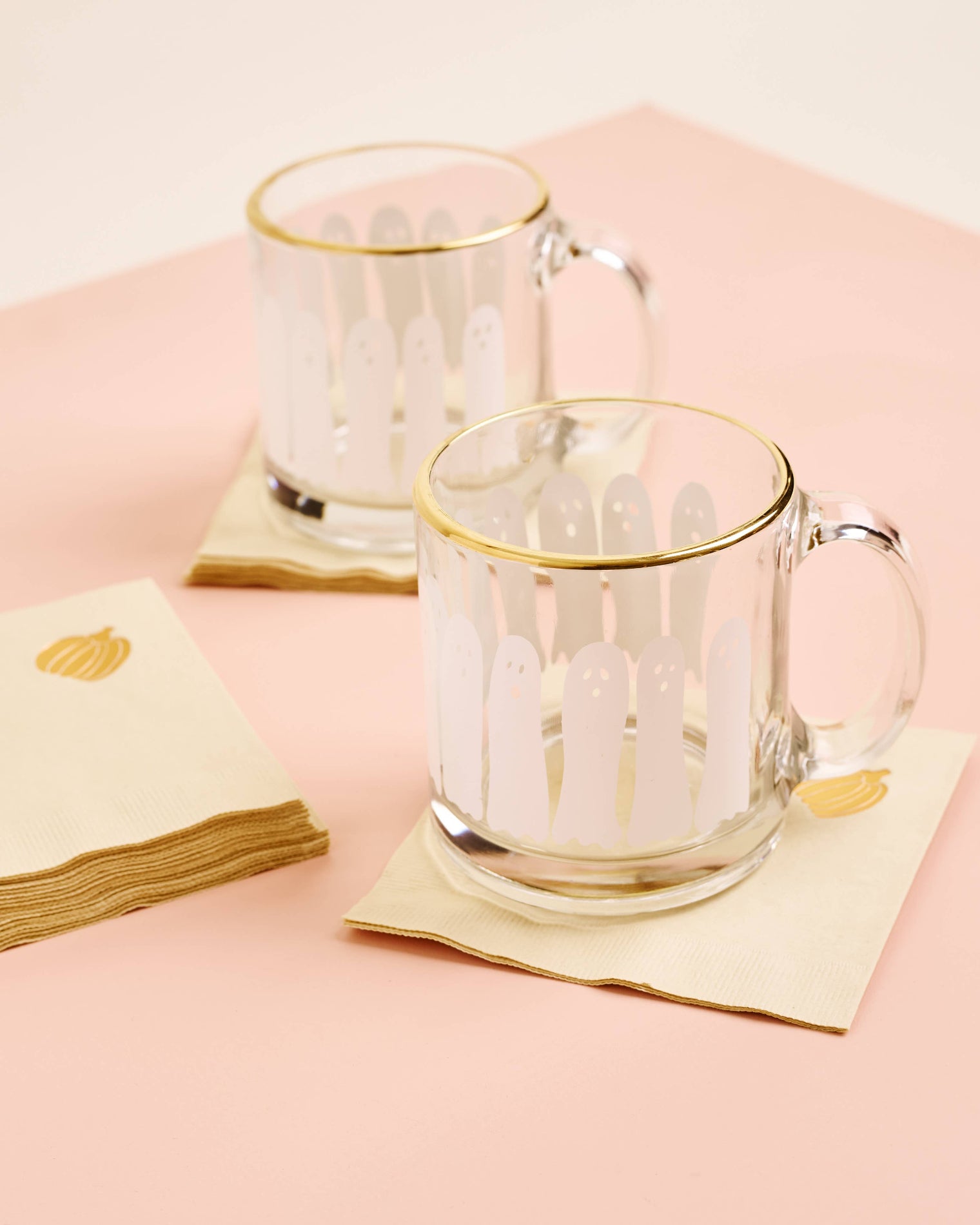 Two glass mugs with gold rims on pink napkins against a pink background, Metallic Pumpkin Beverage Napkin Set