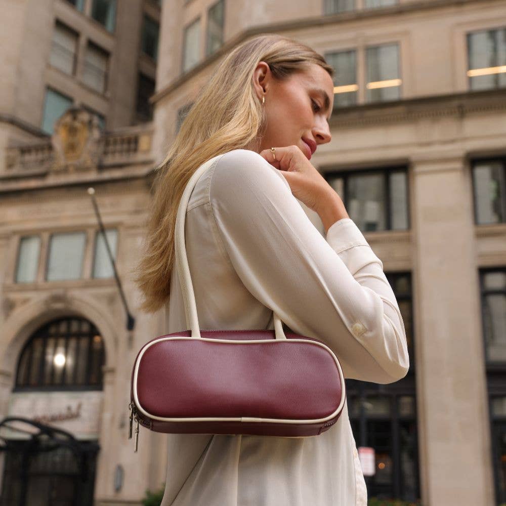 Woman holding a maroon handbag in an urban setting