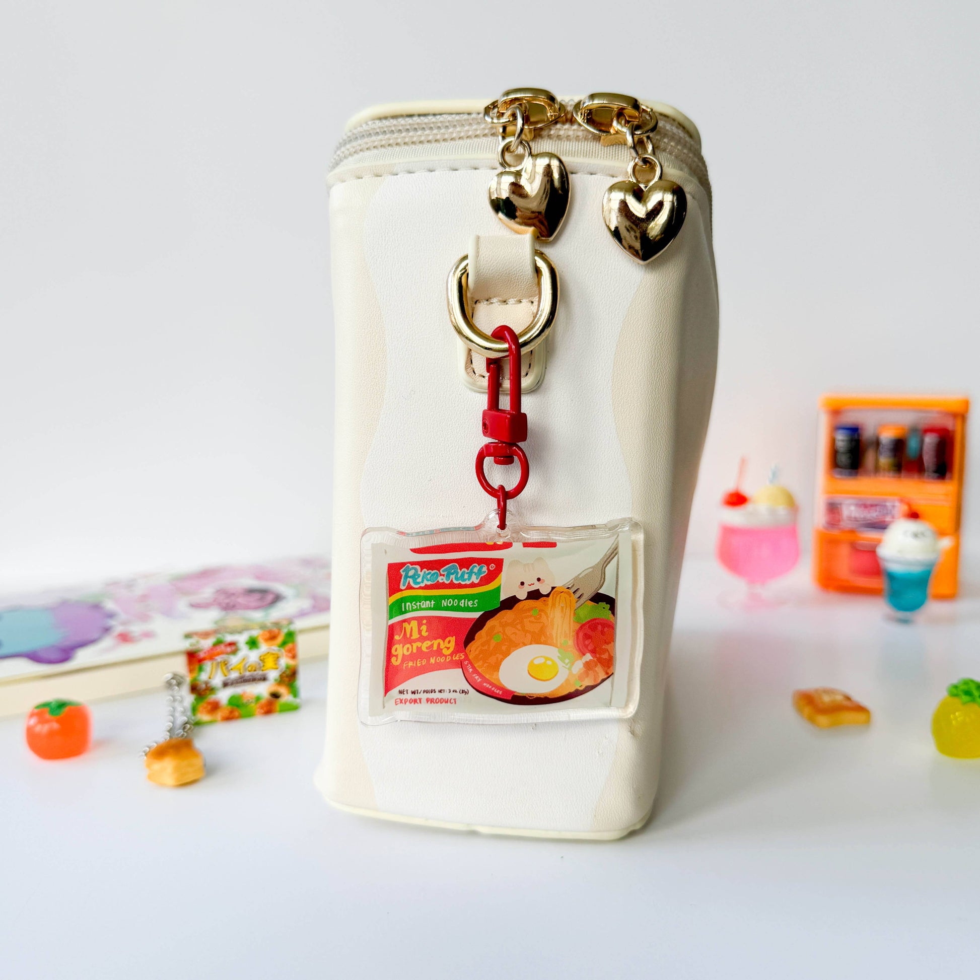 White container with a keychain and heart-shaped charms on a light gray background