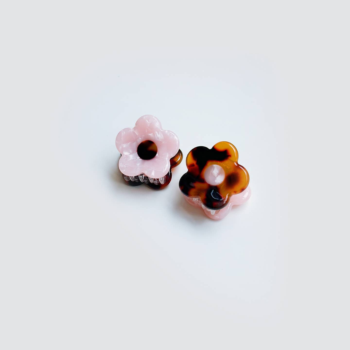 Pair of floral-shaped earrings with tortoiseshell and pink accents on a white background