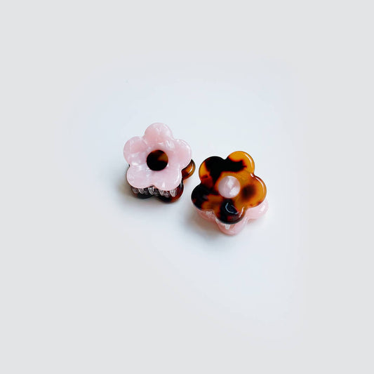 Pair of floral-shaped earrings with tortoiseshell and pink accents on a white background