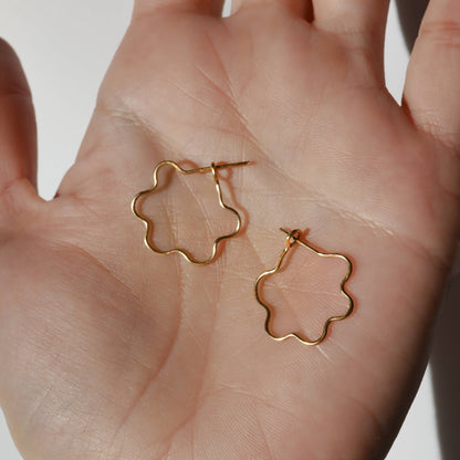 Gold flower-shaped earrings held in a hand against a neutral background, Mini Flora Hoop Earrings in Gold 