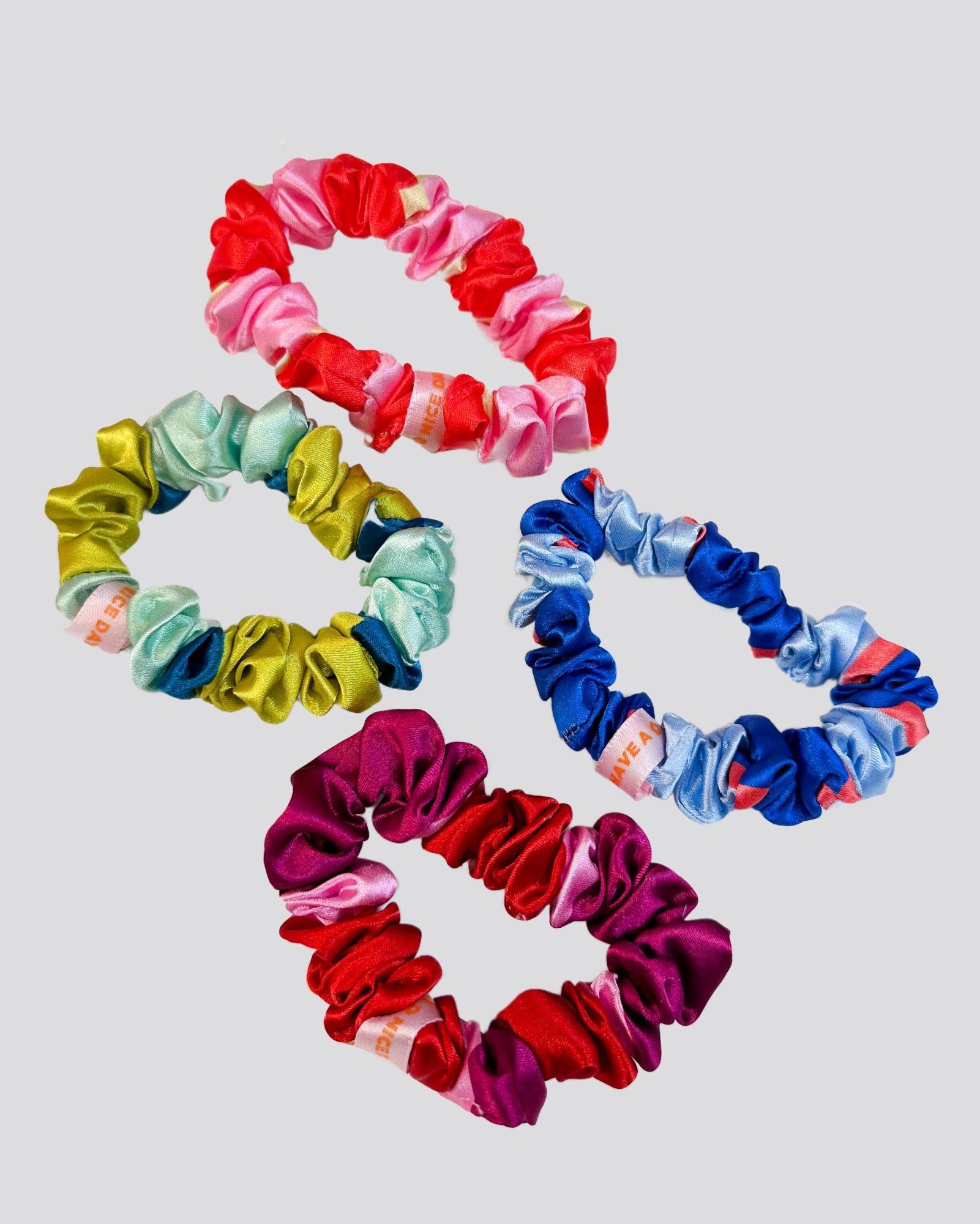 Set of colorful scrunchies arranged in a circular pattern on a light gray background