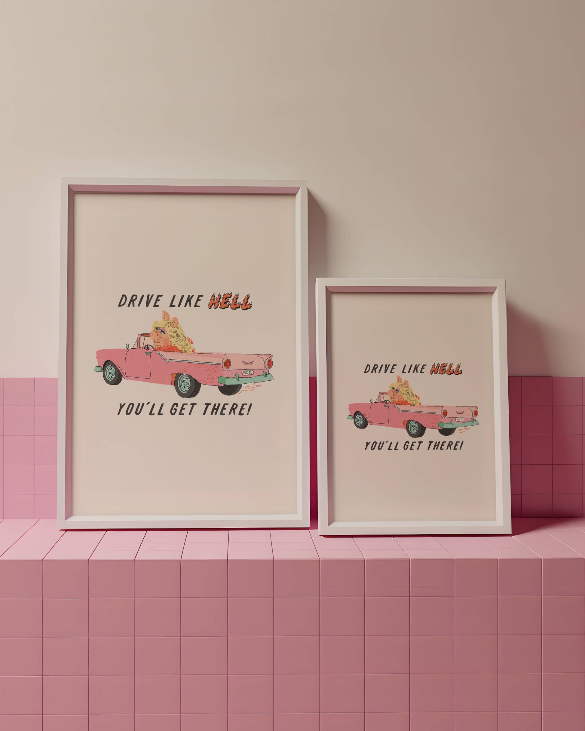 Two framed prints with a pink car illustration and text on a pink tiled wall.