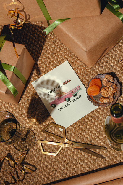 A styled flat-lay of aN ART PRINT WITH THE WORDS  'DRIVE LIKE HELL. YOU'LL GET THERE!'.