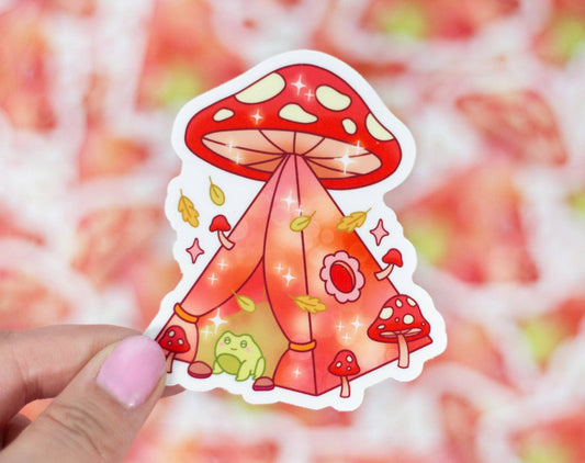 Sticker of a red mushroom with a tent-like structure held by a hand against a colorful background.