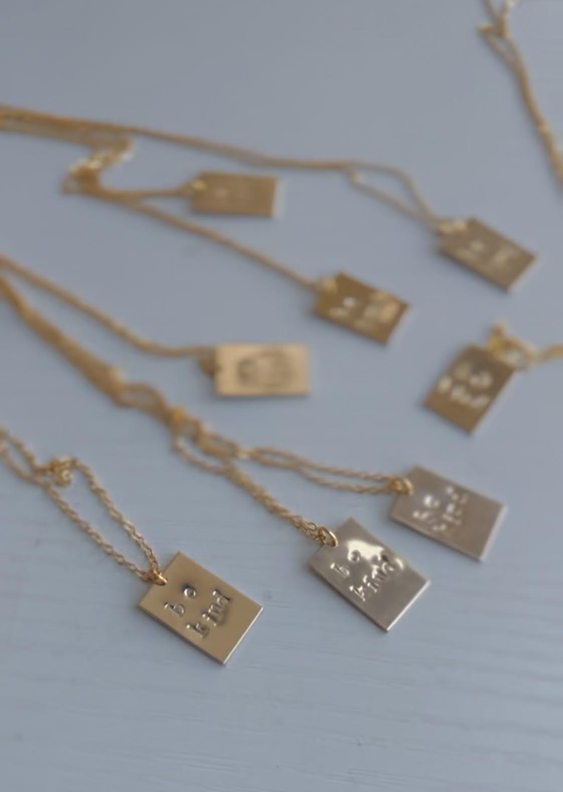 Gold necklaces with square pendants on a light blue background