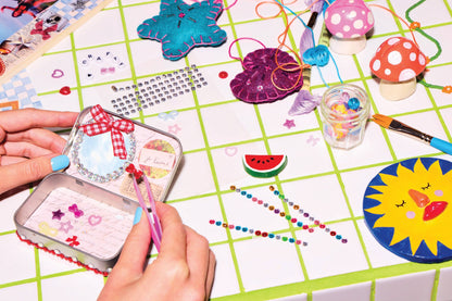Crafting activity with decorative items and tools on a grid surface