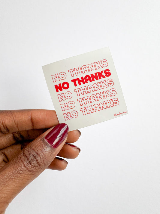 Hand holding a small stickerwith 'No Thanks' text on a white background