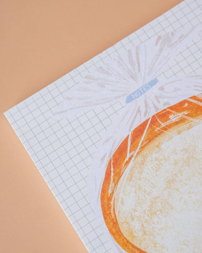 Sheet of paper with grid pattern and printed design on a beige background