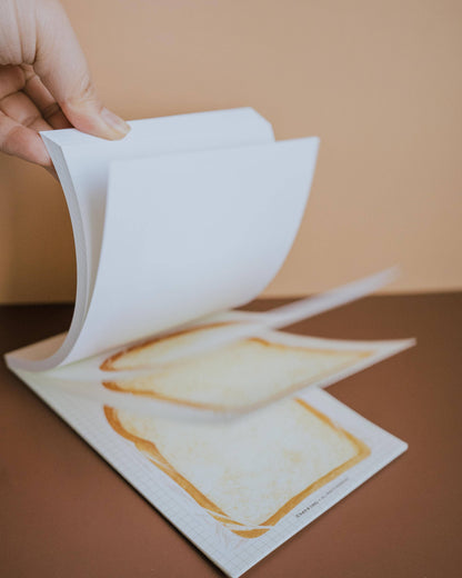 Hand holding a piece of white paper over a printed image on a brown surface