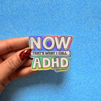 Hand holding a colorful sticker with 'NOW THAT'S WHAT I CALL ADHD' text on a blue background. Now Thats What I Call ADHD Holographic Sticker