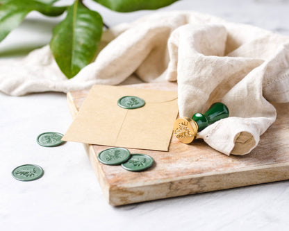 Envelopes with green stamps on a wooden board with a white cloth and plant leaves in the background