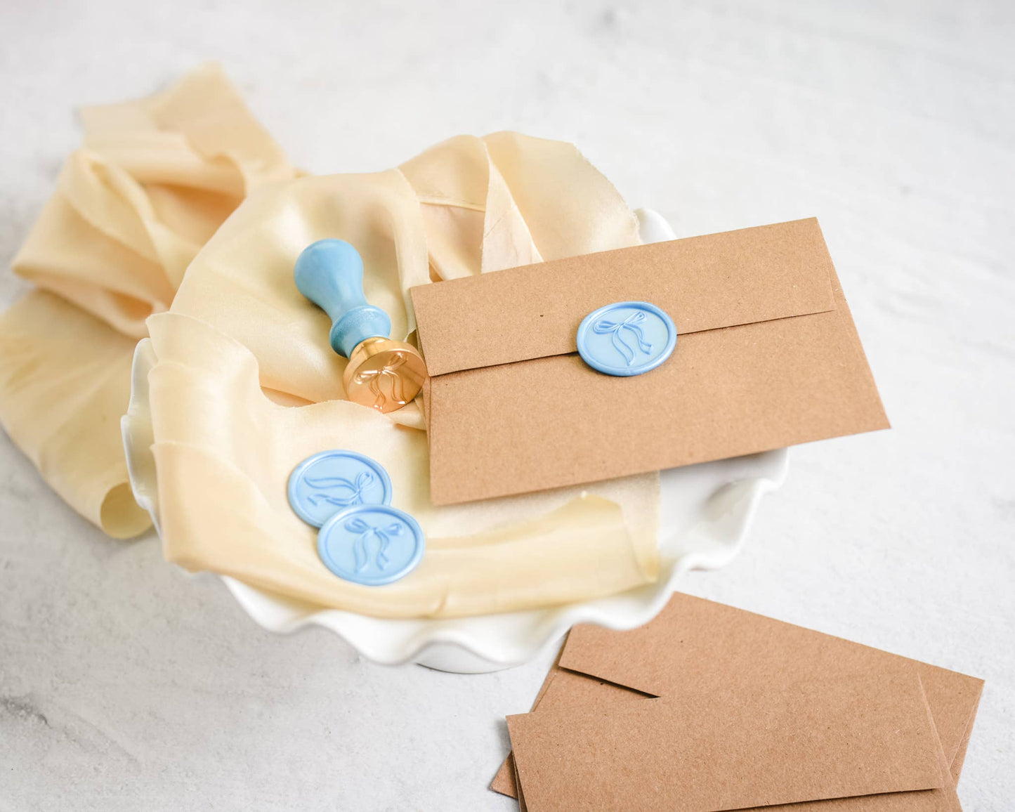 Kraft paper envelopes with wax seals on a white fabric background