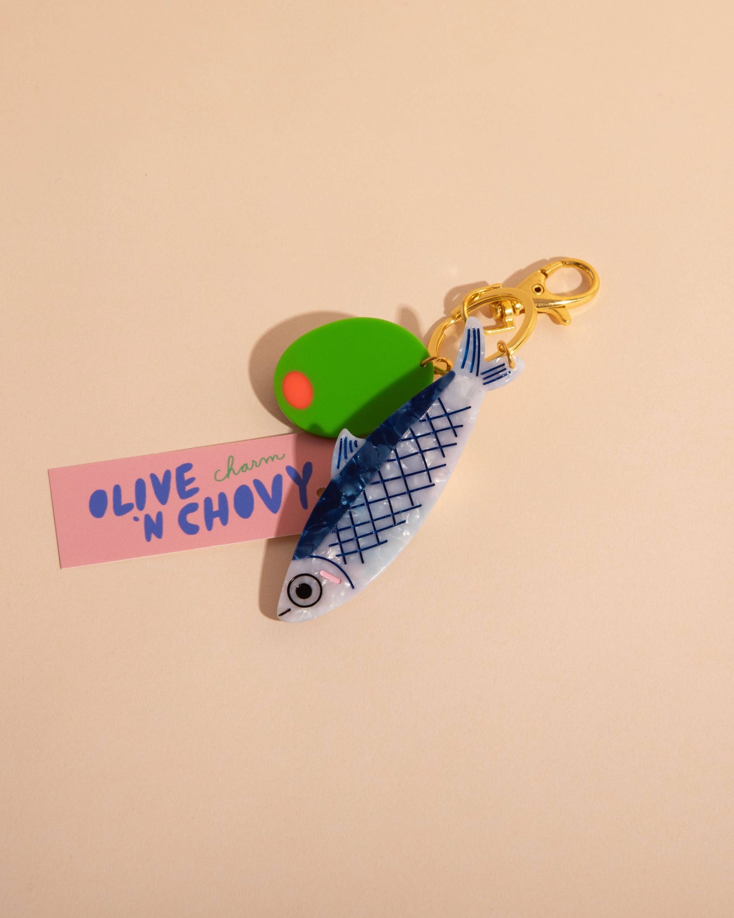 Keychain with green olive and pink label on beige background