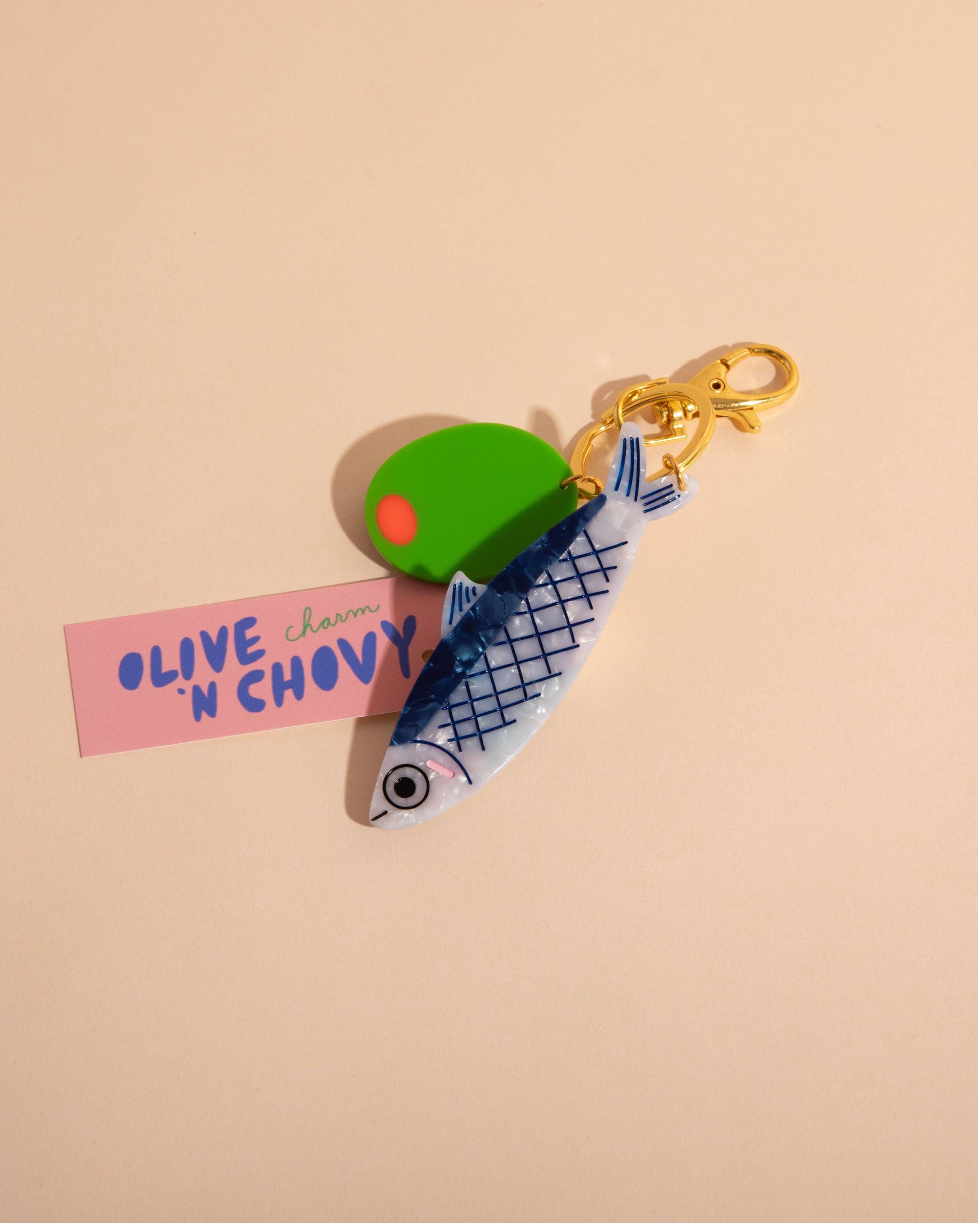 Keychain with green olive and pink label on beige background