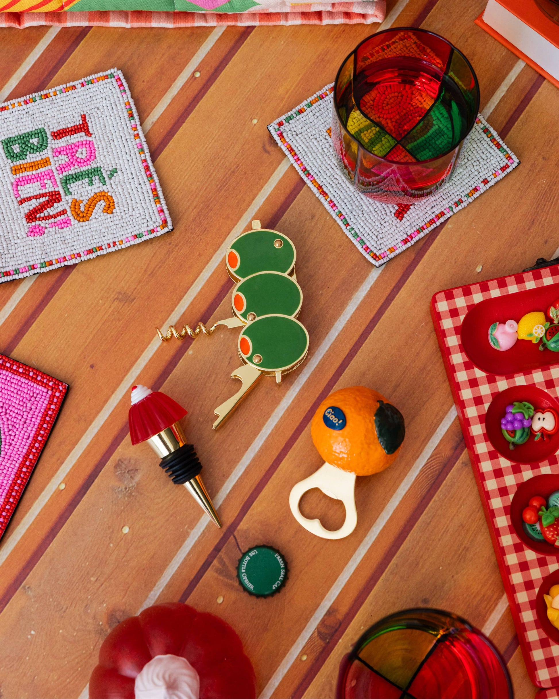 Colorful items including a bottle opener, keychain, and coasters on a wooden surface.