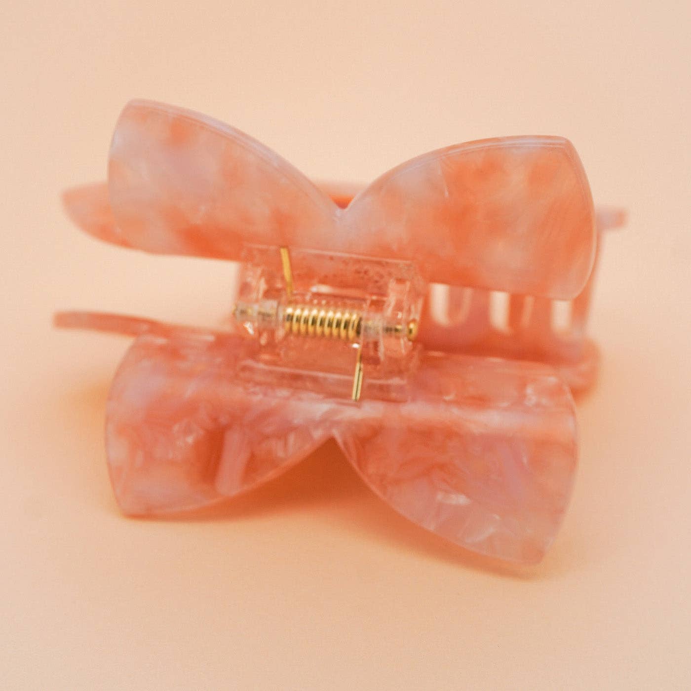 Pink bow-shaped hair clip on a peach background