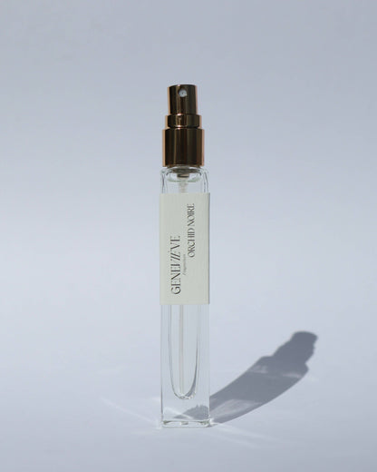 Small clear spray bottle with gold cap on a light gray background