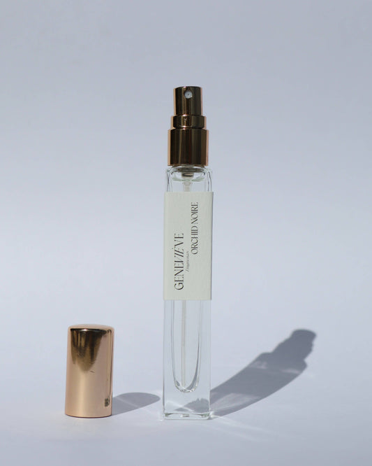 Small perfume bottle with gold cap and visible brand name on a light gray background