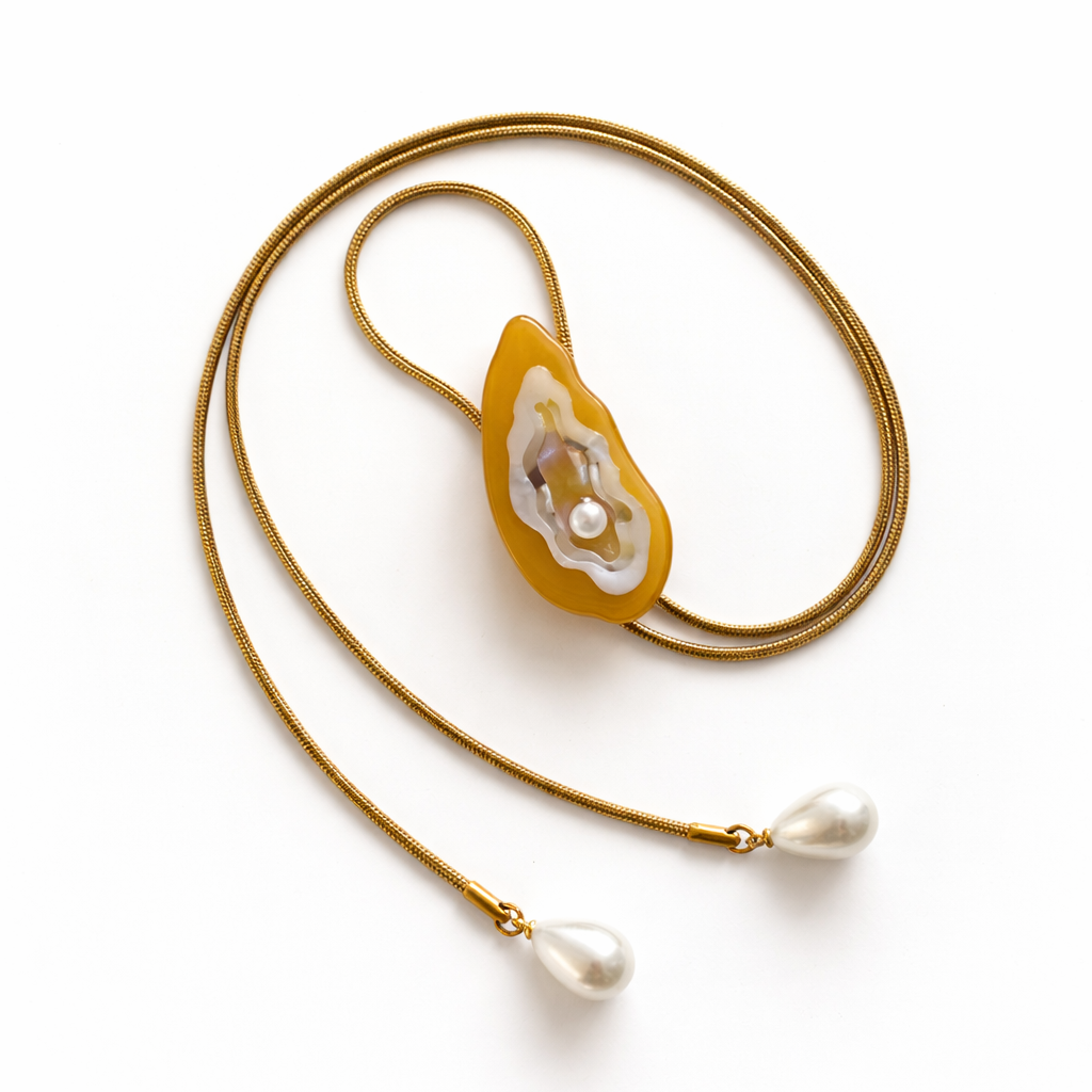 Gold necklace with a unique pendant and pearl drops on a white background