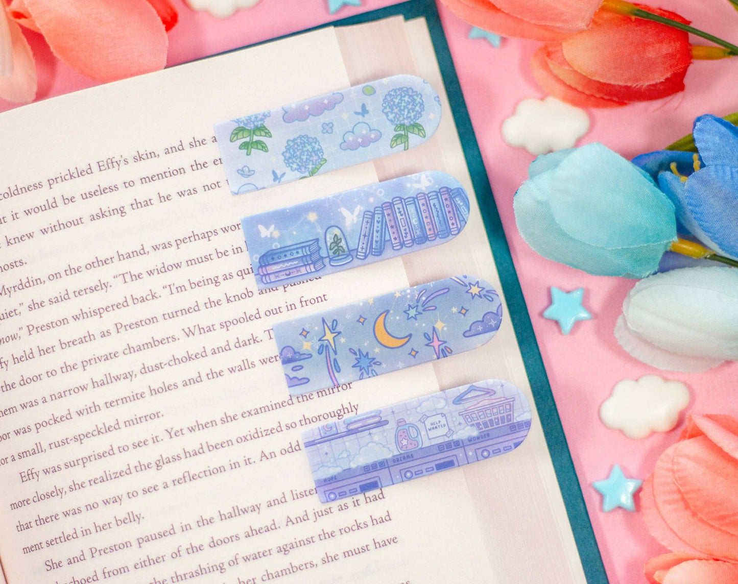 Decorative bookmarks with cartoon designs on a book next to pink tulips