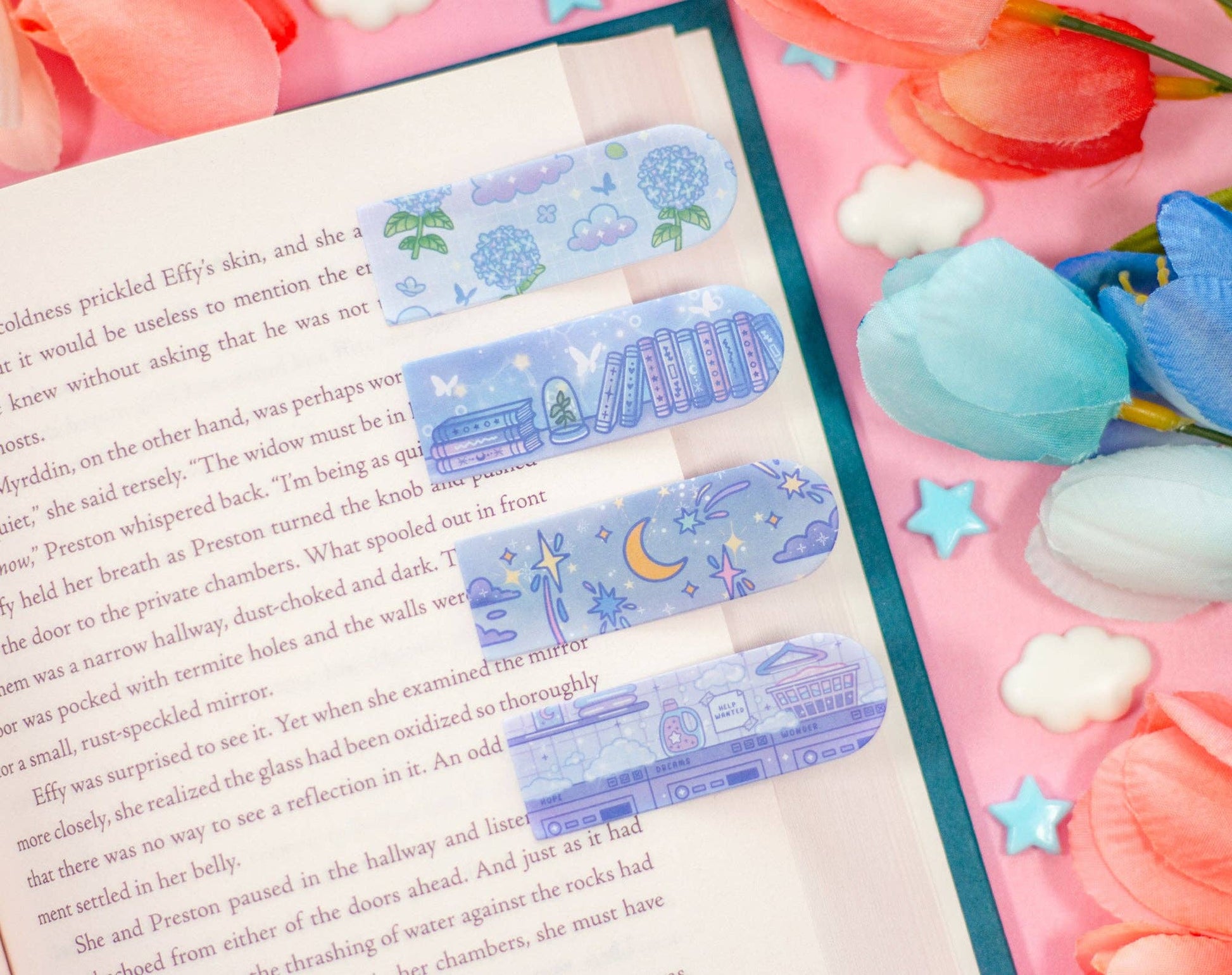 Decorative bookmarks with cartoon designs on a book next to pink tulips