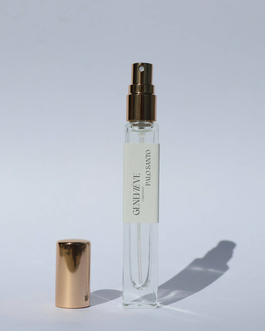 Clear spray bottle with gold cap on a light gray background