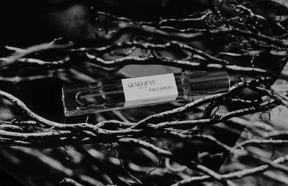 Small bottle of Genevève Palo Santo perfume on a dark, textured surface