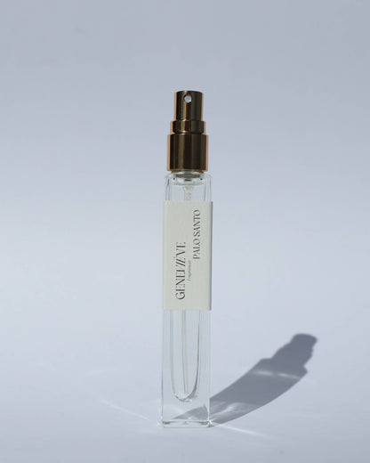 Clear spray bottle with gold cap on a light gray background