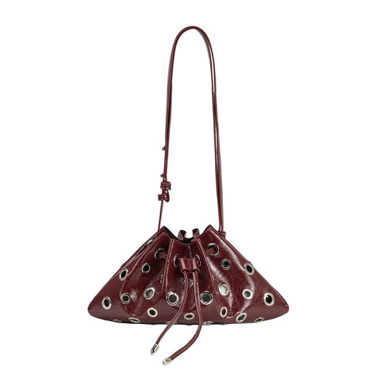 A small, dark burgundy leather bucket bag with a drawstring closure and multiple silver-tone metal grommets, shown against a plain white background.