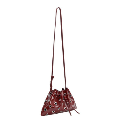 A glossy burgundy leather bucket bag with silver-tone grommets and a long shoulder strap, shown against a plain white background.