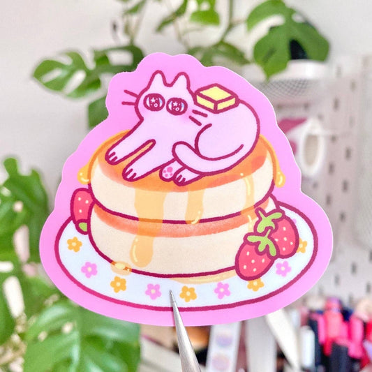 Cartoon cat on a cake with pink border, plant and blurred background