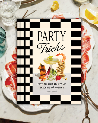 Book titled 'Party Tricks' on a table with food and drinks