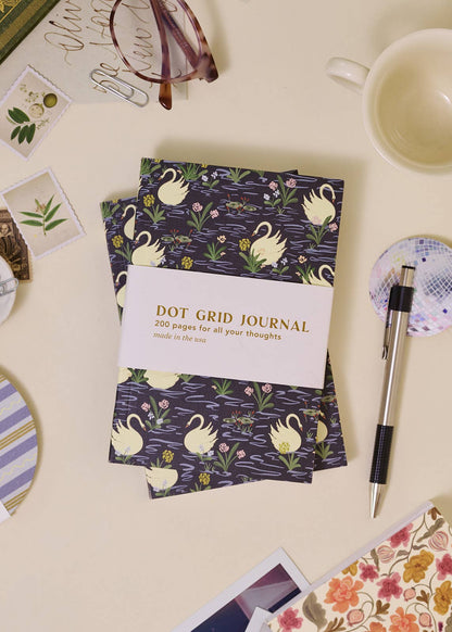 Dot grid journal with swan design on a desk with stationery items
